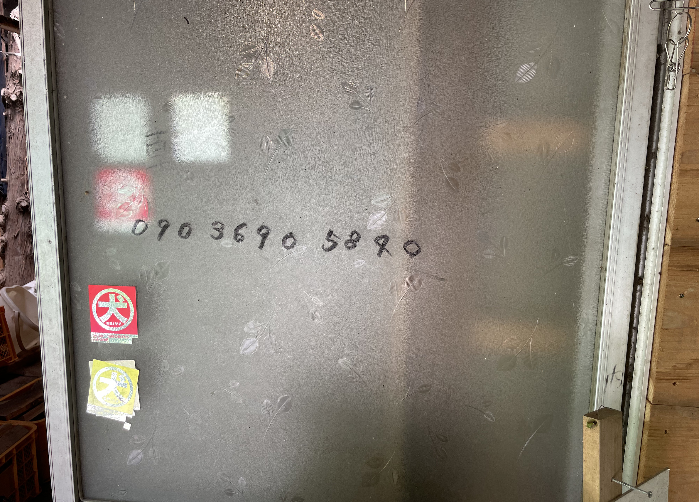 グリーンファームおおたき戸田オートキャンプ場の管理棟ドアに書かれた電話番号